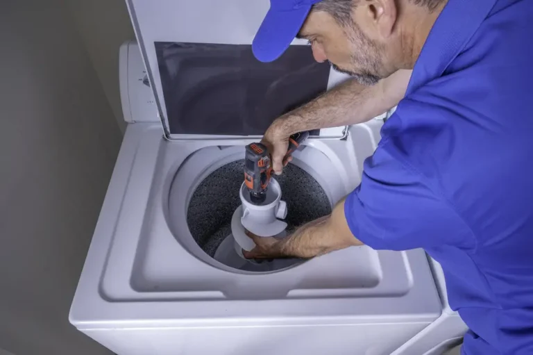 Technician repairing a top load washing machine during troubleshooting of common washer problems
