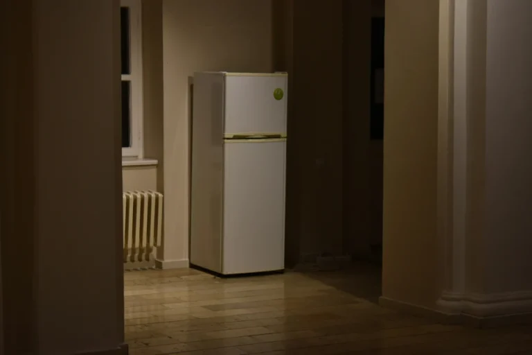 Old two-door refrigerator standing in an empty room